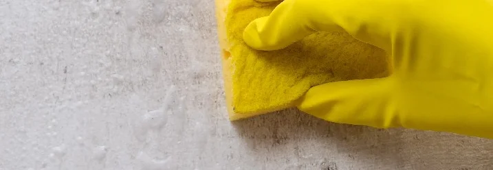 Hand in gelbem Handschuh mit Schwamm